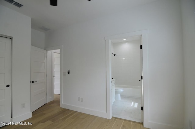 unfurnished bedroom featuring light wood-type flooring and connected bathroom