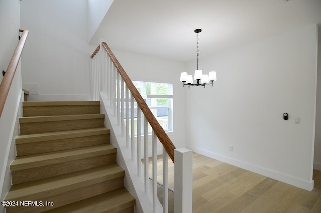 staircase with hardwood / wood-style flooring and an inviting chandelier