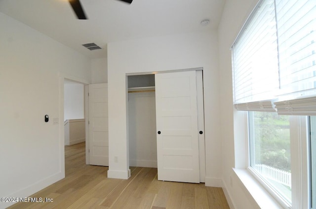 unfurnished bedroom with light hardwood / wood-style floors, a closet, and ceiling fan