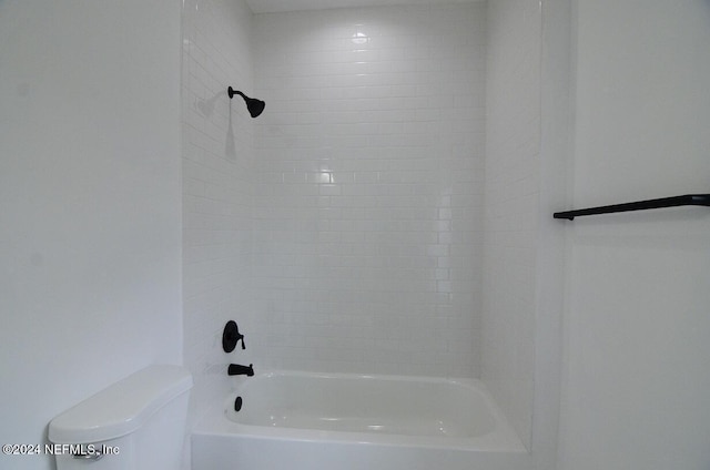 bathroom featuring toilet and tiled shower / bath