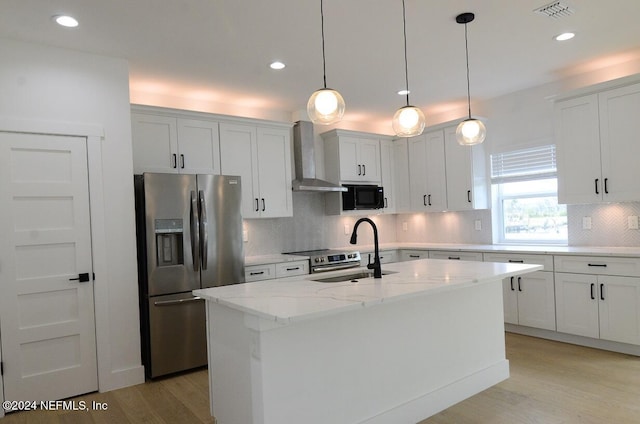 kitchen with wall chimney range hood, sink, a center island with sink, white cabinets, and stainless steel fridge with ice dispenser