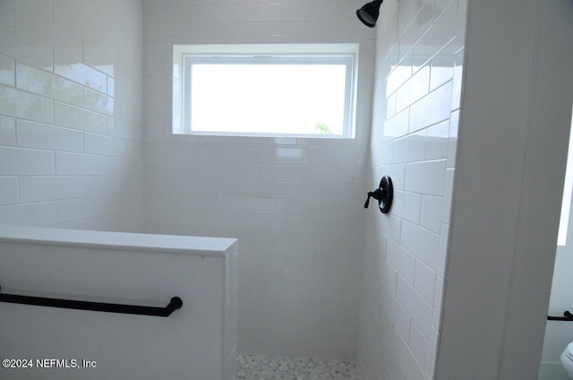 bathroom featuring a tile shower and toilet