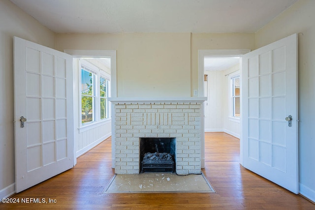 unfurnished living room featuring light hardwood / wood-style floors and a brick fireplace