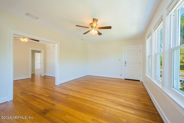 empty room featuring plenty of natural light, ceiling fan, and light wood-type flooring