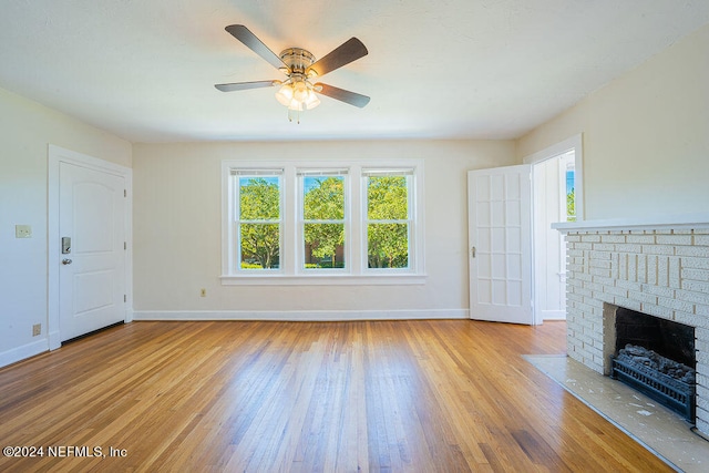 unfurnished living room featuring a brick fireplace, ceiling fan, and light wood-type flooring