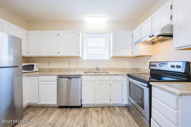 kitchen with wall chimney exhaust hood, white cabinets, appliances with stainless steel finishes, and sink