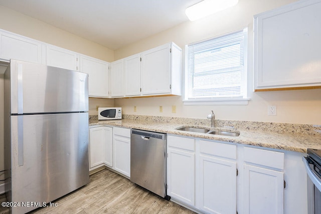 kitchen with white cabinets, stainless steel appliances, light hardwood / wood-style flooring, and light stone counters