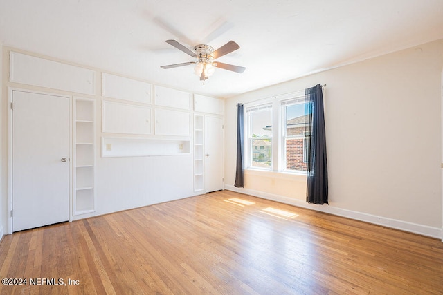 empty room with built in shelves, light hardwood / wood-style floors, and ceiling fan