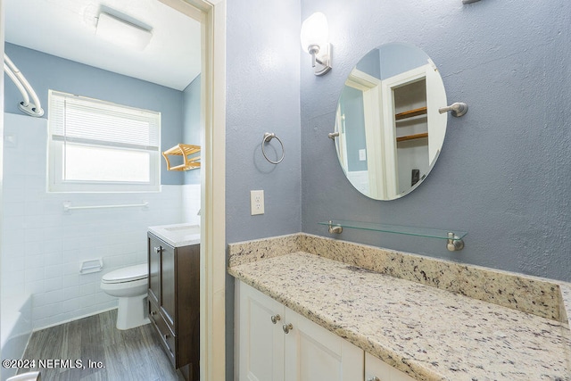 full bathroom with tile walls, toilet, bathing tub / shower combination, wood-type flooring, and vanity