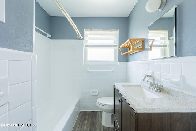 full bathroom featuring hardwood / wood-style floors, large vanity, toilet, and tile walls