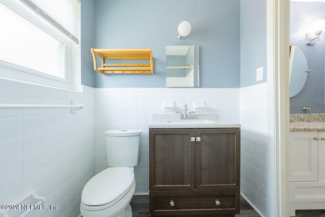 bathroom featuring wood-type flooring, tile walls, toilet, and vanity