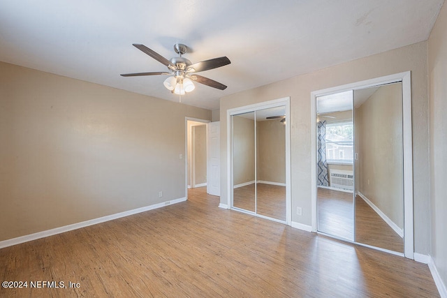 unfurnished bedroom featuring multiple closets, ceiling fan, and light hardwood / wood-style flooring