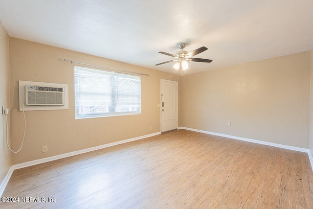 empty room featuring a wall unit AC, light hardwood / wood-style floors, and ceiling fan