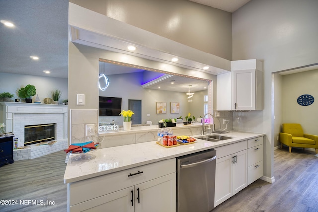 kitchen featuring white cabinetry, a fireplace, sink, light hardwood / wood-style flooring, and dishwasher