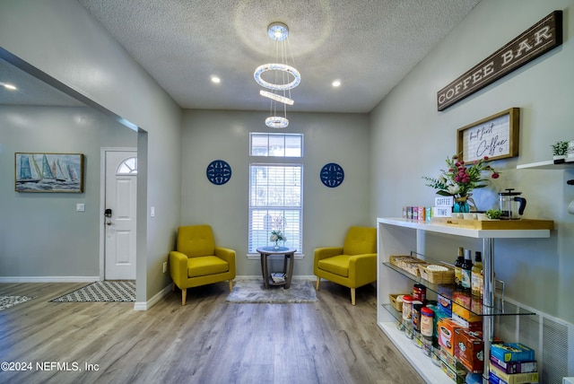 living area featuring a chandelier, light hardwood / wood-style flooring, and a textured ceiling