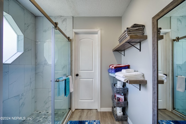 bathroom featuring an enclosed shower, a textured ceiling, and hardwood / wood-style flooring