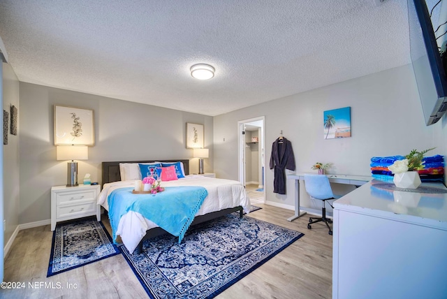 bedroom with a textured ceiling and light wood-type flooring