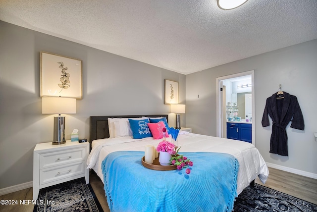 bedroom featuring a textured ceiling, ensuite bath, and dark hardwood / wood-style floors