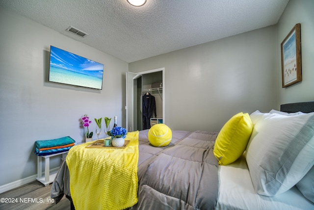 bedroom with wood-type flooring, a closet, and a textured ceiling