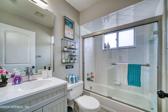 full bathroom with toilet, combined bath / shower with glass door, large vanity, and a textured ceiling