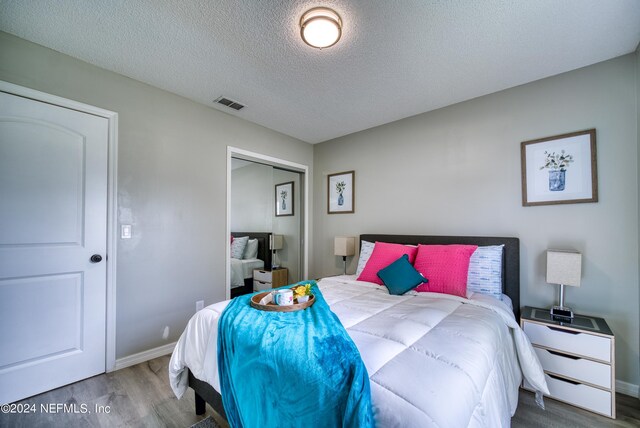 bedroom featuring a closet, a textured ceiling, and hardwood / wood-style flooring