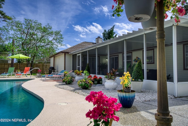 rear view of house featuring a fenced in pool and a patio area