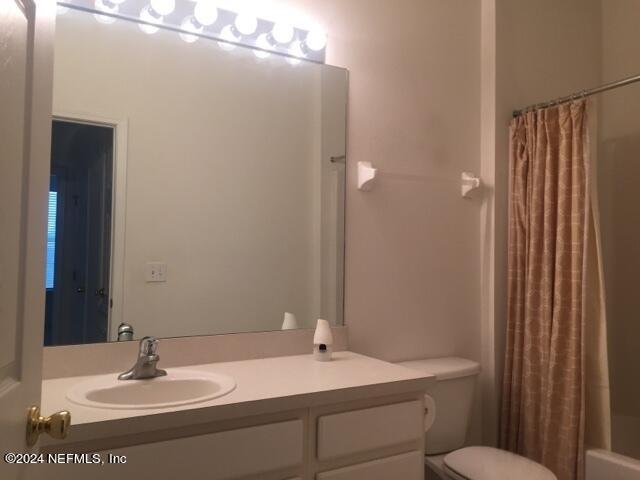 full bathroom with toilet, shower / tub combo with curtain, and vanity