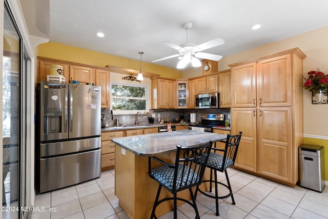 kitchen featuring ceiling fan, light stone counters, a breakfast bar, backsplash, and stainless steel appliances