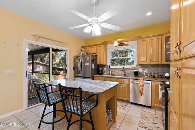 kitchen with stainless steel appliances, light tile flooring, ceiling fan, tasteful backsplash, and light stone counters