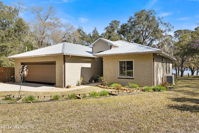 view of front facade featuring a front yard, a garage, and central air condition unit