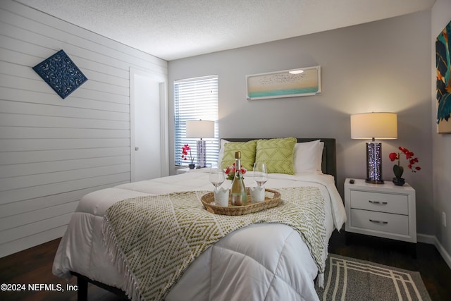 bedroom with dark hardwood / wood-style floors and a textured ceiling