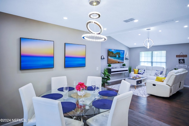 dining room with dark hardwood / wood-style flooring, vaulted ceiling, and a notable chandelier