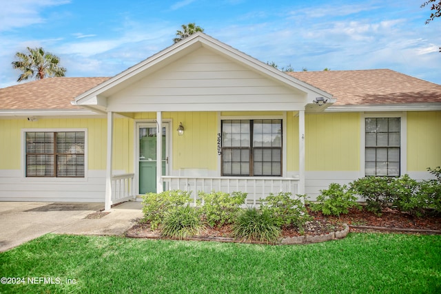 ranch-style home featuring a front lawn and covered porch