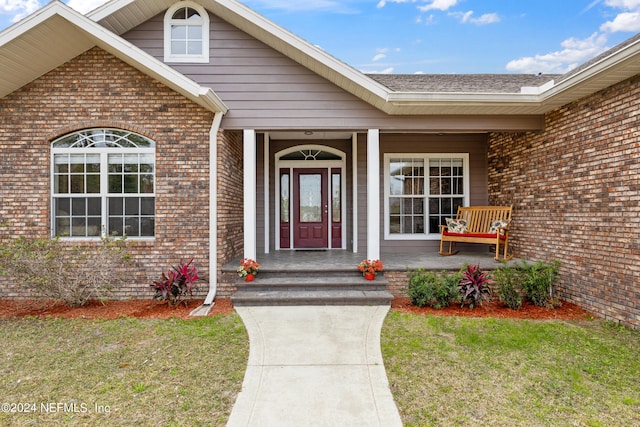 entrance to property featuring a porch and a lawn