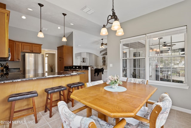 tiled dining area featuring lofted ceiling, sink, and ceiling fan with notable chandelier