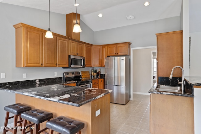 kitchen featuring kitchen peninsula, a kitchen bar, sink, stainless steel appliances, and dark stone counters