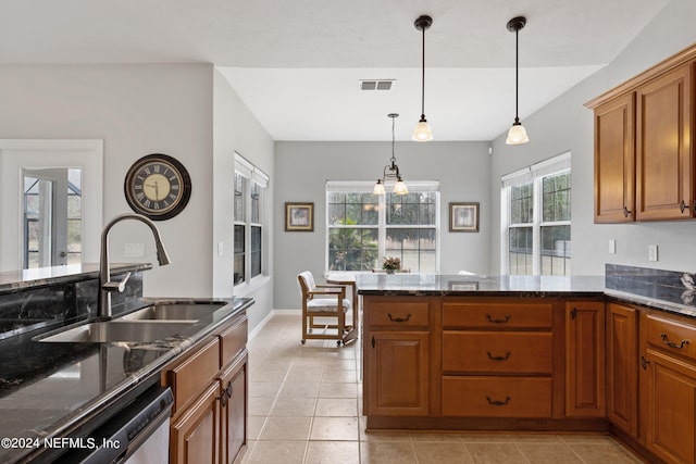 kitchen with light tile floors, dark stone countertops, sink, and pendant lighting