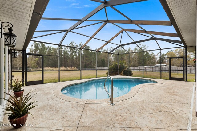 view of pool featuring glass enclosure, a lawn, and a patio