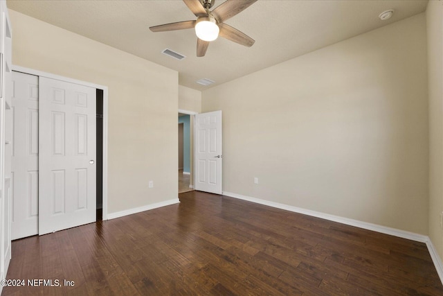 unfurnished bedroom featuring dark wood-type flooring, a closet, and ceiling fan