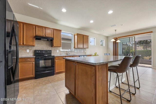 kitchen featuring decorative backsplash, a kitchen island, black appliances, pendant lighting, and a textured ceiling