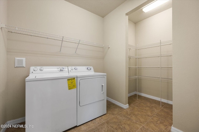 laundry area with independent washer and dryer and light tile patterned floors