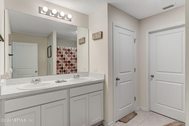 bathroom with vanity with extensive cabinet space, dual sinks, and tile floors