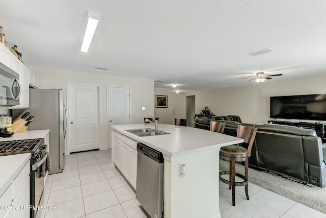 kitchen with an island with sink, ceiling fan, sink, appliances with stainless steel finishes, and white cabinetry