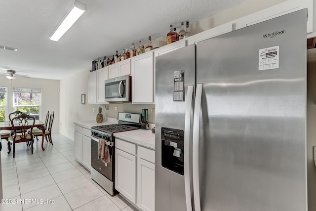 kitchen with white cabinets, light tile flooring, stainless steel appliances, and ceiling fan