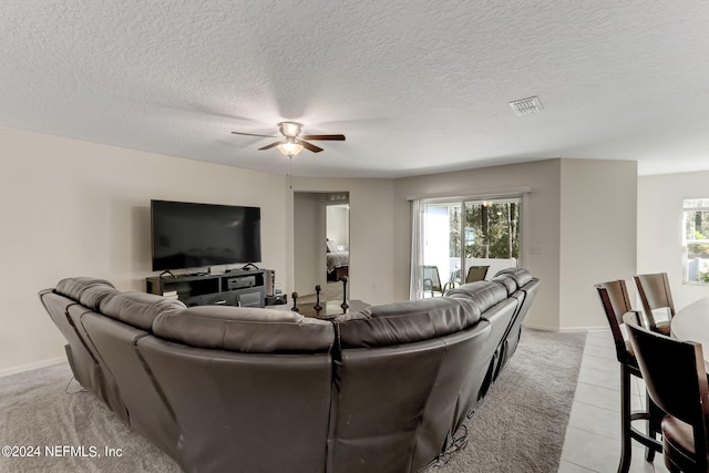 living room featuring light tile floors, ceiling fan, a textured ceiling, and a wealth of natural light