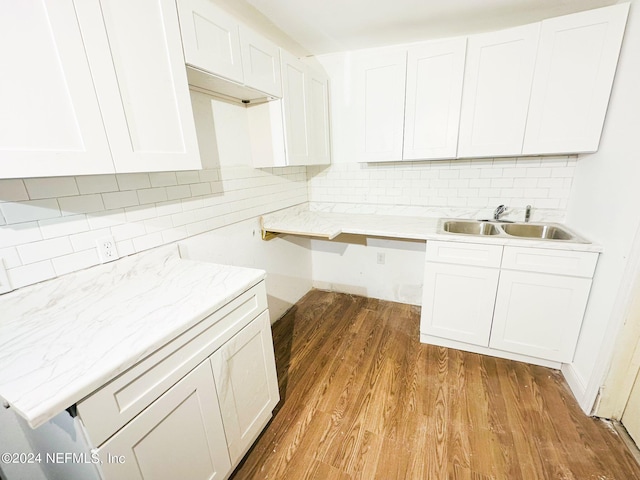 kitchen with backsplash, sink, light wood-type flooring, and white cabinetry