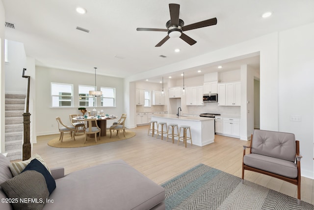 living area with stairway, light wood-type flooring, visible vents, and recessed lighting