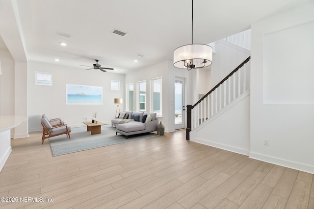 living area featuring recessed lighting, visible vents, light wood-type flooring, baseboards, and stairs