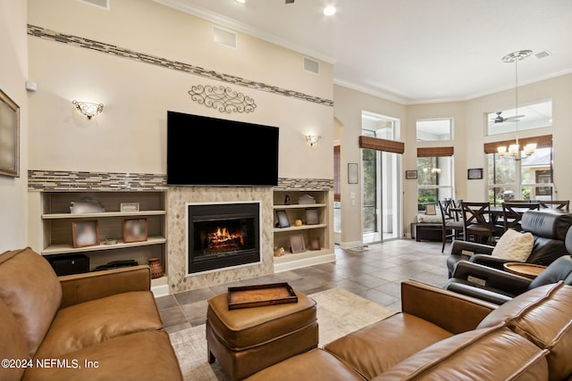 tiled living room featuring plenty of natural light, ornamental molding, and a chandelier