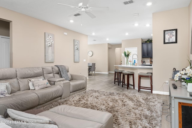 living room with light hardwood / wood-style floors and ceiling fan